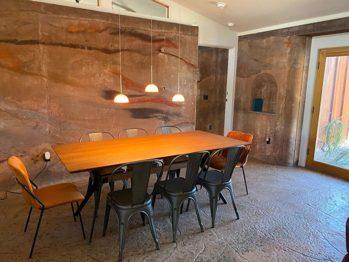 A conference room with a long wooden table, black chairs, and pendant lighting.