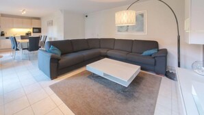 A modern living room with a sectional sofa, a coffee table, and a dining area with chairs.