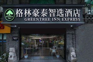 The exterior of the Greentree Inn Express, featuring a modern facade with glass doors, a visible seating area inside, and traditional Chinese lion statues at the entrance. - Greentree Inn Nanjing Zhongshan Mausoleum Scenic Area Zhongling Street Subway Station Express Hotel (Nanjing)