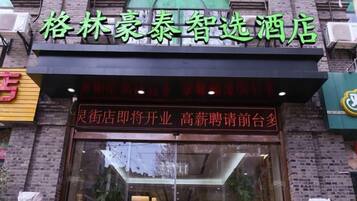 A hotel facade with a large glass entrance, a brick exterior, and a sign with Chinese characters.