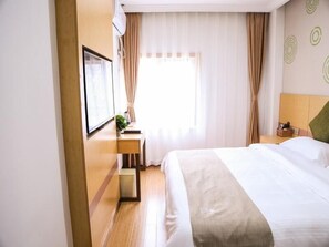 A hotel room with a bed, a desk with a lamp, a window with curtains, and a wall with circular patterns. - Greentree Inn Nanjing Zhongshan Mausoleum Scenic Area Zhongling Street Subway Station Express Hotel (Nanjing)
