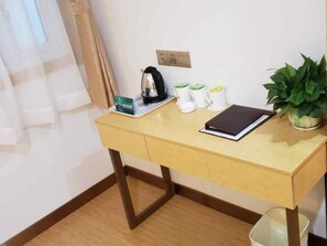 A small wooden desk with a kettle, a black notebook, and a potted plant. - Greentree Inn Nanjing Zhongshan Mausoleum Scenic Area Zhongling Street Subway Station Express Hotel (Nanjing)