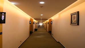 A hotel hallway with a long corridor, signs indicating room numbers, and a framed artwork on the wall. - Greentree Inn Nanjing Zhongshan Mausoleum Scenic Area Zhongling Street Subway Station Express Hotel (Nanjing)