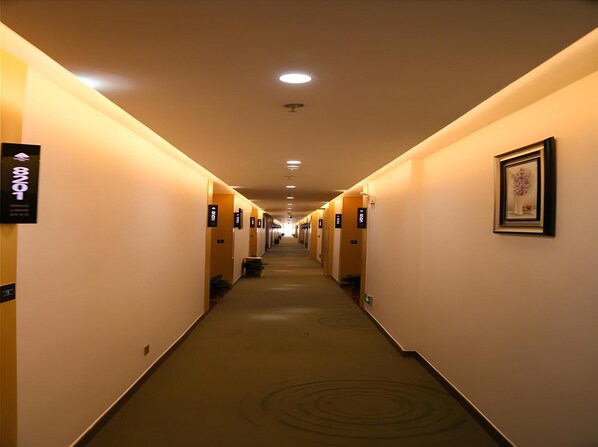 A hotel hallway with a long corridor, signs indicating room numbers, and a framed artwork on the wall. - Greentree Inn Nanjing Zhongshan Mausoleum Scenic Area Zhongling Street Subway Station Express Hotel (Nanjing)
