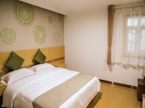 A hotel room with a bed, two pillows, a nightstand, a wall with circular patterns, and a window with curtains. - Greentree Inn Nanjing Zhongshan Mausoleum Scenic Area Zhongling Street Subway Station Express Hotel (Nanjing)