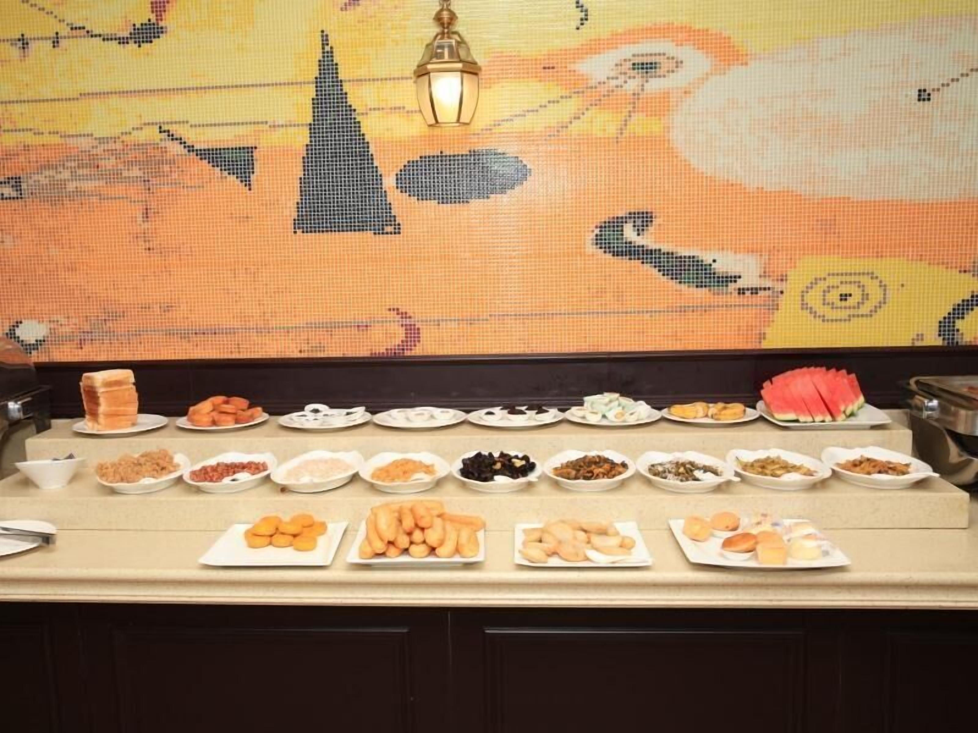 A buffet table with various food items and a decorative wall in the background.