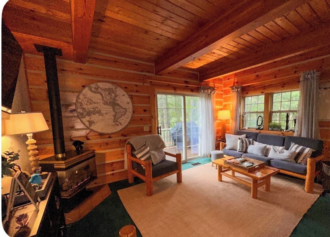 A cozy cabin interior with a fireplace, a sofa, and a coffee table.