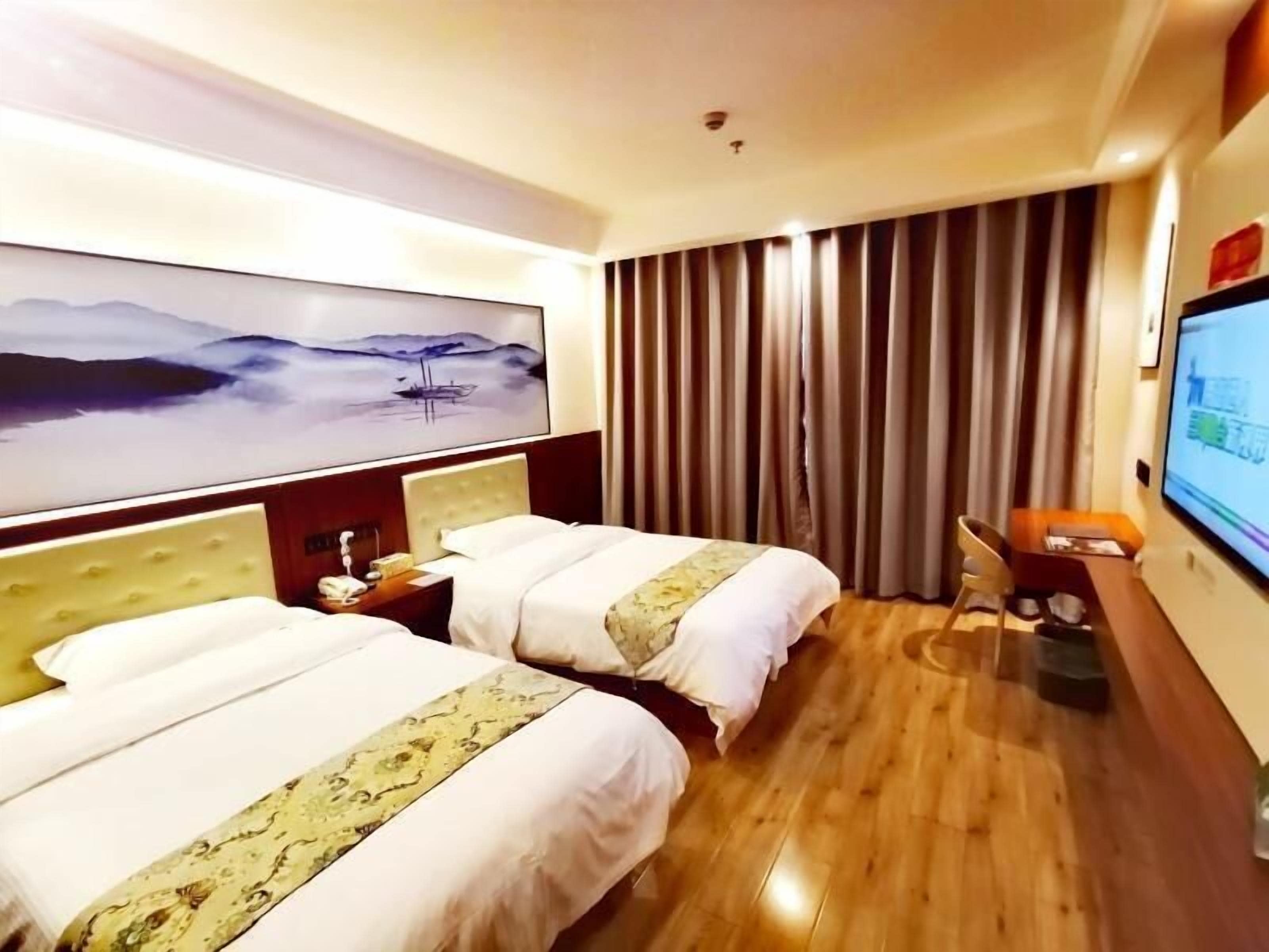A hotel room with two beds, a large painting on the wall, a TV, and a wooden floor.