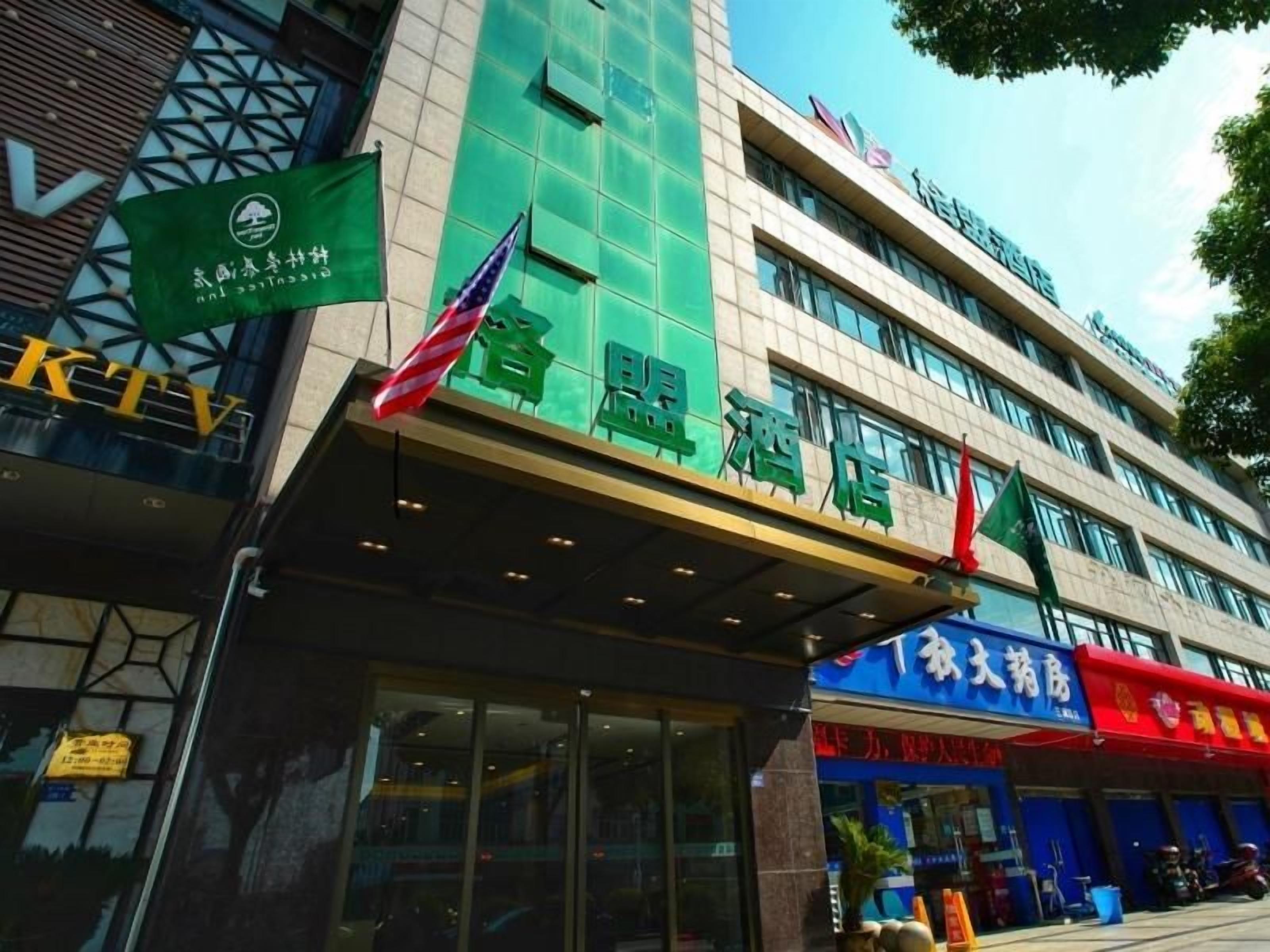A hotel with a green facade and multiple flags.