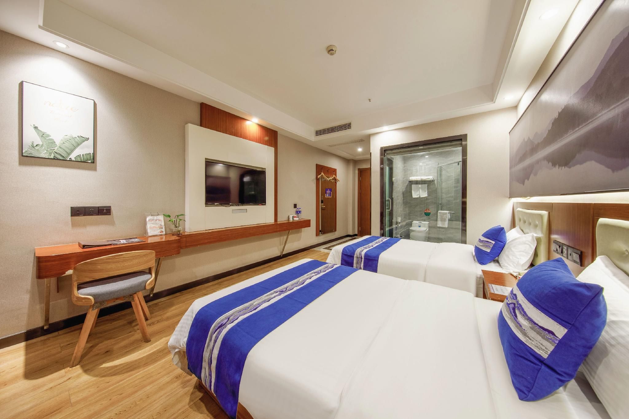 Habitació d'hotel amb dos llits, escriptori, televisió i zona de banyera amb dutxa.