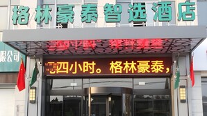 A hotel entrance with a glass door, a digital sign displaying the time, and flags on either side. - Greentree Inn Express Yancheng Tinghu District Environmental Protection Industrial Park (Yancheng)