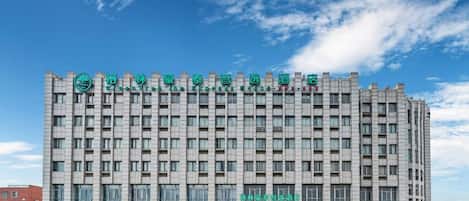 Un edificio hotelero de varios pisos con un diseño arquitectónico moderno, que presenta una señalización destacada en la parte superior.