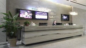 A reception desk with two monitors, a marble counter, and potted plants. - Greentree Inn Express Yancheng Tinghu District Environmental Protection Industrial Park (Yancheng)