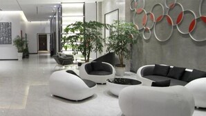 A modern lobby with a seating area featuring white and black sofas, a coffee table, and potted plants. - Greentree Inn Express Yancheng Tinghu District Environmental Protection Industrial Park (Yancheng)