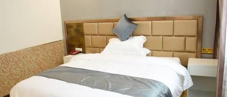 A neatly made bed with a headboard, a bedside table with a lamp, and a patterned wall.