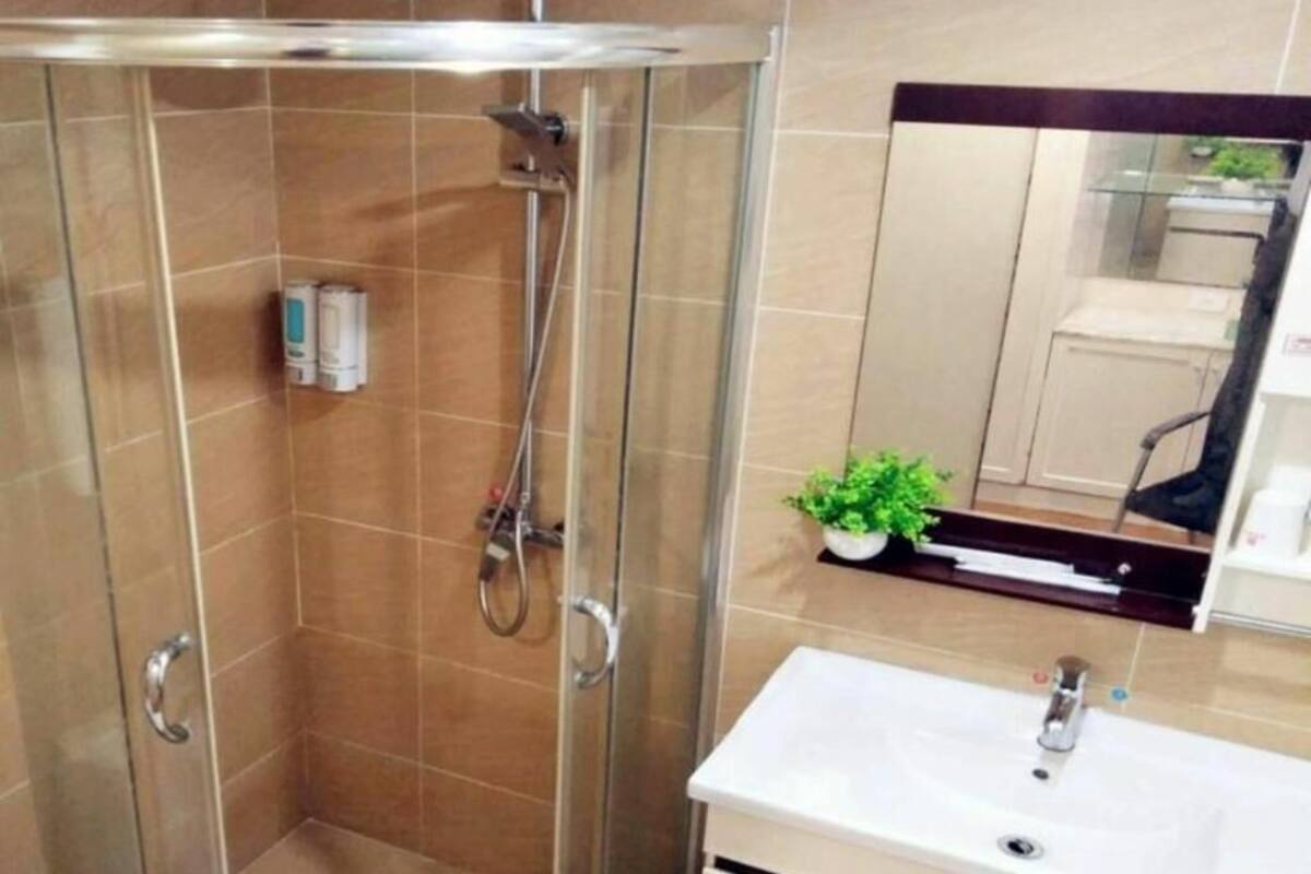 Un baño con ducha de vidrio, lavamanos y espejo.