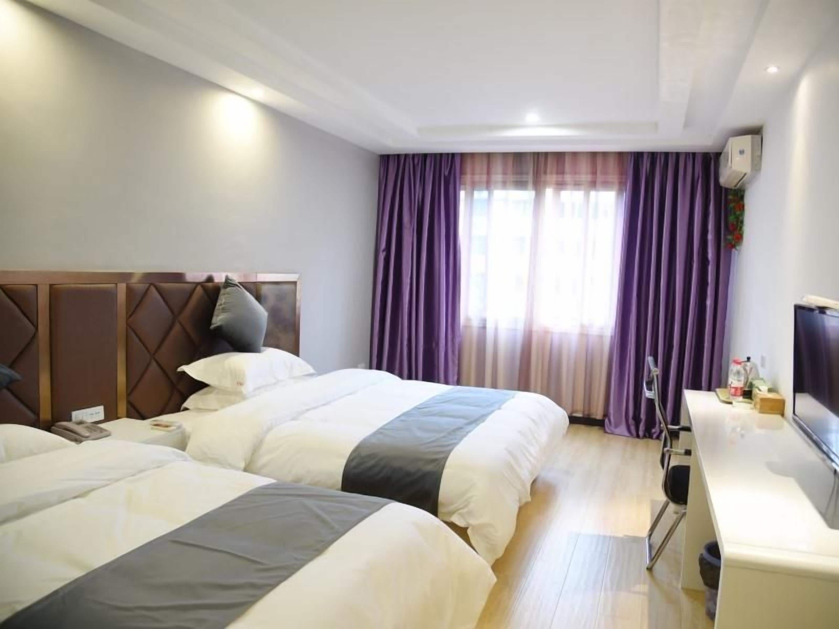 Een hotelkamer met twee bedden, een bureau en een televisie.