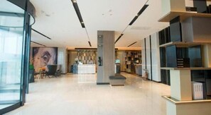 A modern hotel lobby with a reception desk, seating area, and a large wall mural. - Echarm Hotel Wuhan Guanggu Biology City (Wuhan)