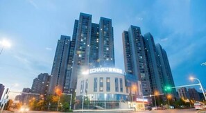 A high-rise building with multiple floors, large windows, and a prominent sign. - Echarm Hotel Wuhan Guanggu Biology City (Wuhan)