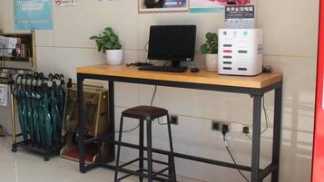 A desk with a computer, a stool, and a radiator.