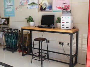 Un escritorio con una computadora, un taburete y un radiador.