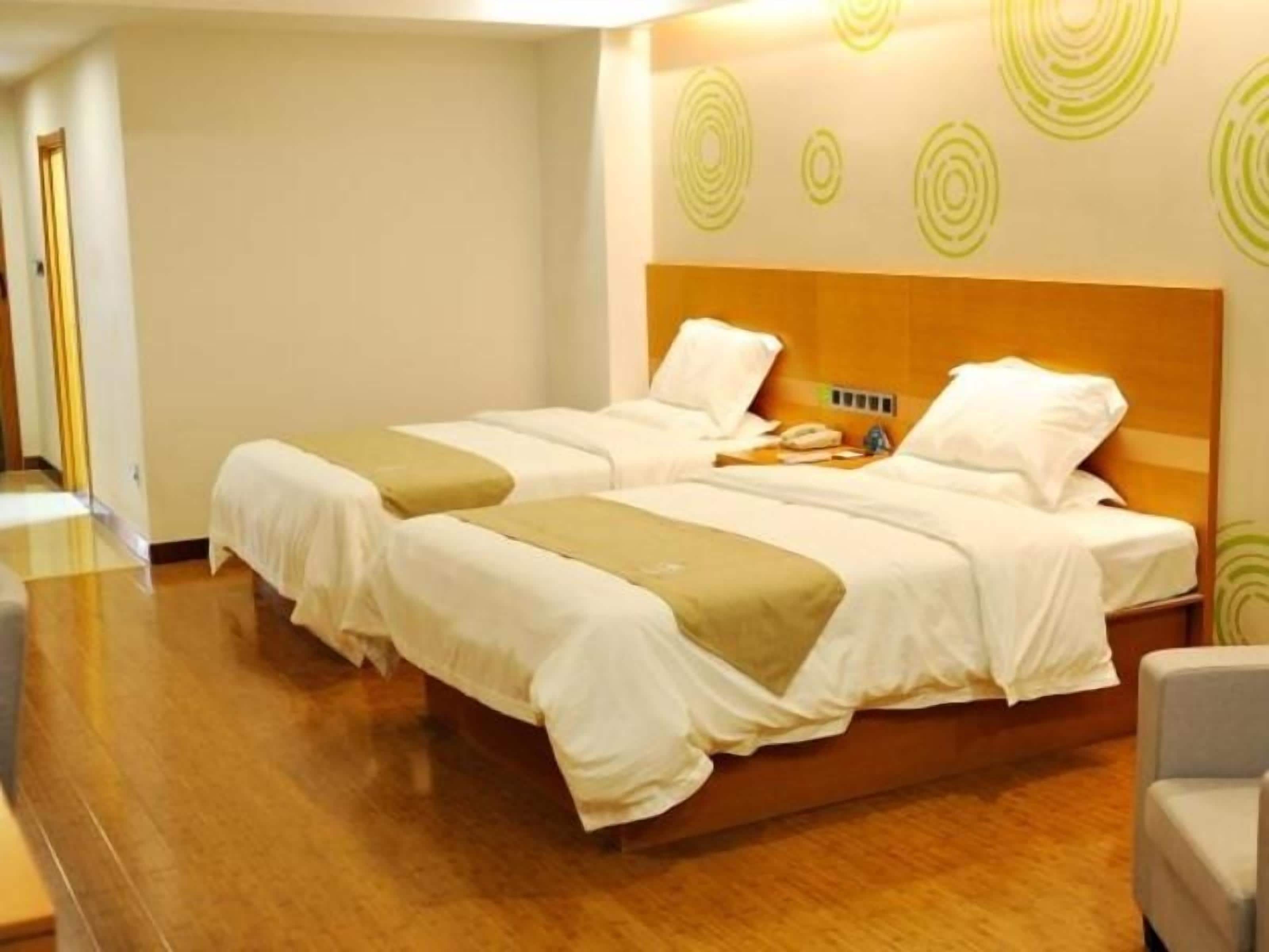A hotel room with two beds, a wooden headboard, and a bedside table with a phone.