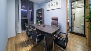A conference room with a wooden table, black chairs, a bookshelf, and a framed sign on the wall. - Greentree Inn Hangzhou Fuyang Wildlife Park Wisdom Hotel (Hangzhou)