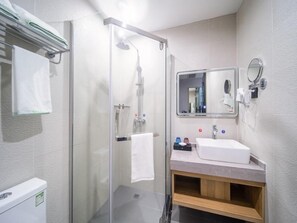 A modern bathroom with a glass shower enclosure, a sink with a mirror, and a towel rack.