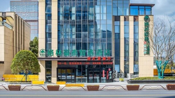 A modern hotel with a glass facade, a prominent green logo, and a sign indicating a 25% discount for booking. - Greentree Inn Hangzhou Fuyang Wildlife Park Wisdom Hotel (Hangzhou)