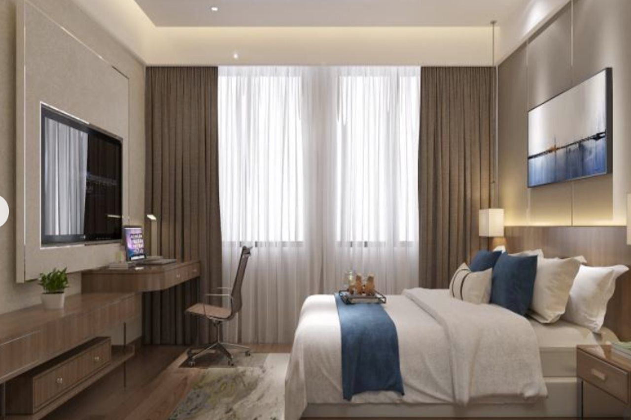 Ein modernes Hotelzimmer mit Bett, Schreibtisch, Stuhl und einem Flachbildfernseher.