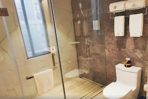 Ein Badezimmer mit einer Duschkabine, einer Toilette und einem Handtuchhalter mit zwei Handtüchern.