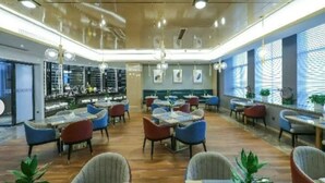 A spacious restaurant with multiple tables and chairs, a bar area, and large windows with blinds. - GYA Jiangsu Provinceyancheng City Oubao Liya Life Plaza Hotel (Yancheng)