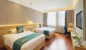 Ein Hotelzimmer mit zwei Betten, einem Schreibtisch, einem Fernseher und einem großen Fenster mit Vorhängen.