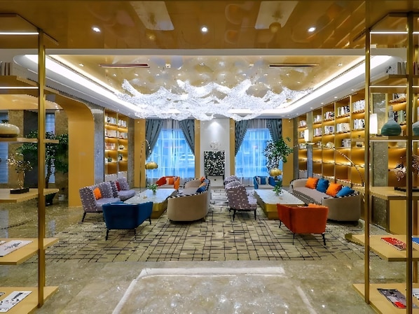 A spacious lounge area with multiple seating options, a central coffee table, and a large bookshelf filled with books.