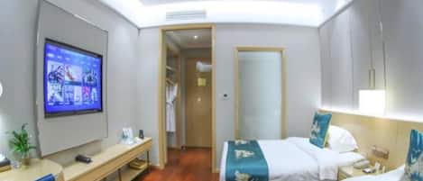 A hotel room with a bed, bedside table, TV, desk, chair, and a mirror.