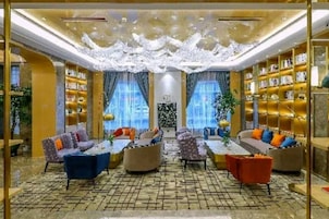 Un hall de hotel con una zona de estar central, estanterías y un techo decorativo.