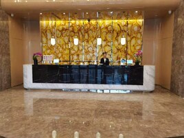 Un mostrador de recepción con encimera de mármol, una recepcionista y una pared con diseño de mármol.
