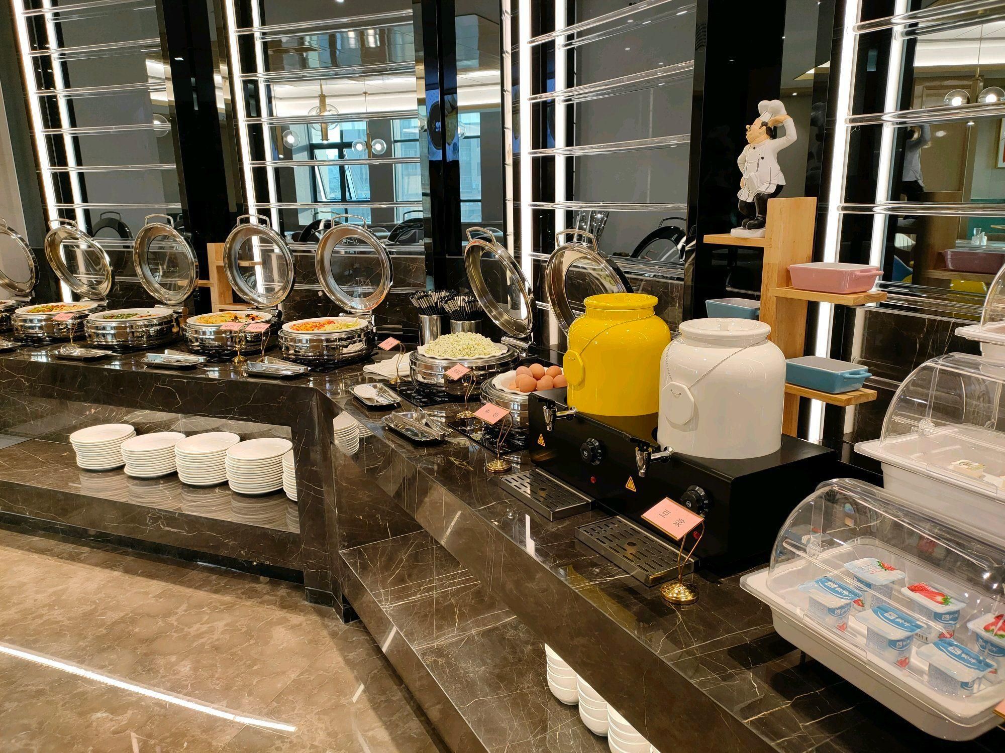 Ein Buffetbereich mit verschiedenen Speisebehältern, Tellern und Besteck.