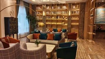 A modern lounge area with a central seating arrangement, a bookshelf, and a decorative ceiling light.