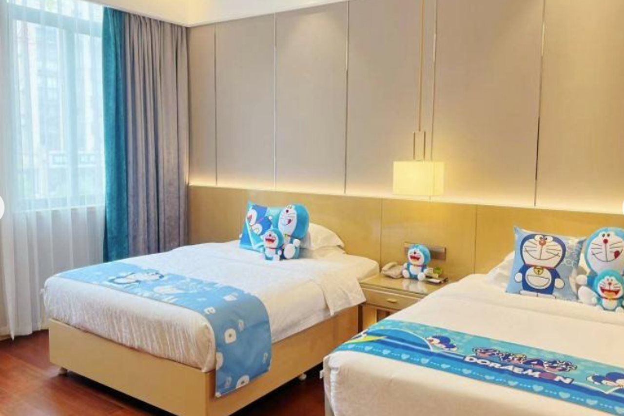 A hotel room with two beds, each adorned with Doraemon-themed bedding.