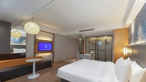A modern hotel room with a large bed, a small round table, a sofa, a TV, and a glass-enclosed shower area. - Starway Hotel (Taixing Wuyue Plaza Jichuan North Road) (Taixing)