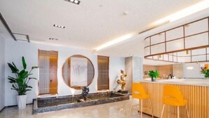 A modern hotel lobby with a reception desk, two yellow chairs, a large mirror, and a decorative fountain. - Starway Hotel (Taixing Wuyue Plaza Jichuan North Road) (Taixing)