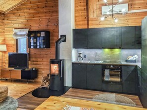 Un interno moderno con soffitto in legno, camino, angolo cottura e televisore.