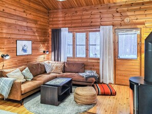 A cozy cabin interior with a sofa, a coffee table, a television, and a fireplace.