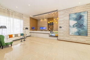 A hotel lobby with a reception desk, seating area, and a large abstract painting.