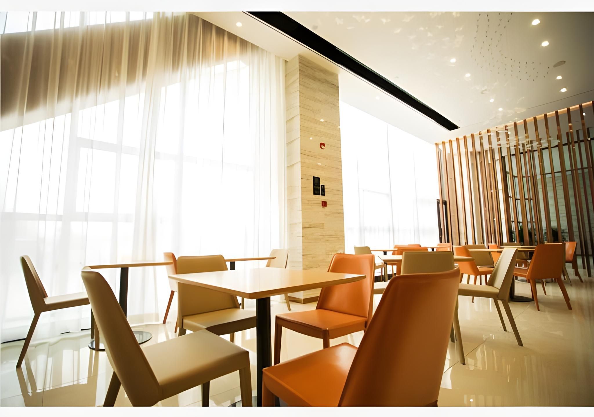 A modern dining area with tables and chairs, large windows, and a wooden partition.