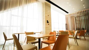 A modern dining area with tables and chairs, large windows, and a wooden partition.