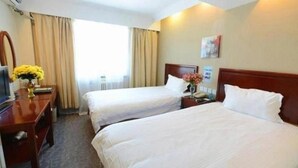 Ein Hotelzimmer mit zwei Betten, einem Schreibtisch, einem Stuhl und einem Fenster mit Vorhängen.