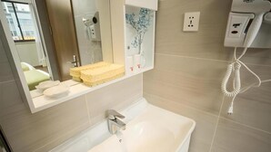 Ein Badezimmer mit einem weißen Waschbecken, einem Spiegel, einem Fön und einem Telefon.