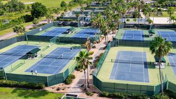 Vue aérienne d’un complexe de tennis doté de plusieurs courts, entouré de palmiers et de verdure.